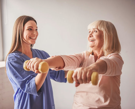 caregiver assisting senior woman in doing exercise