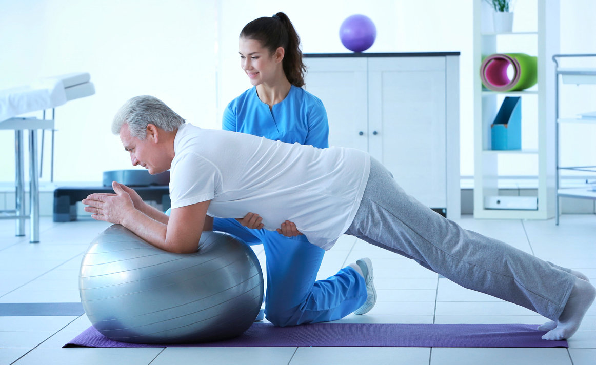 caregiver assisting senior man in doing exercise