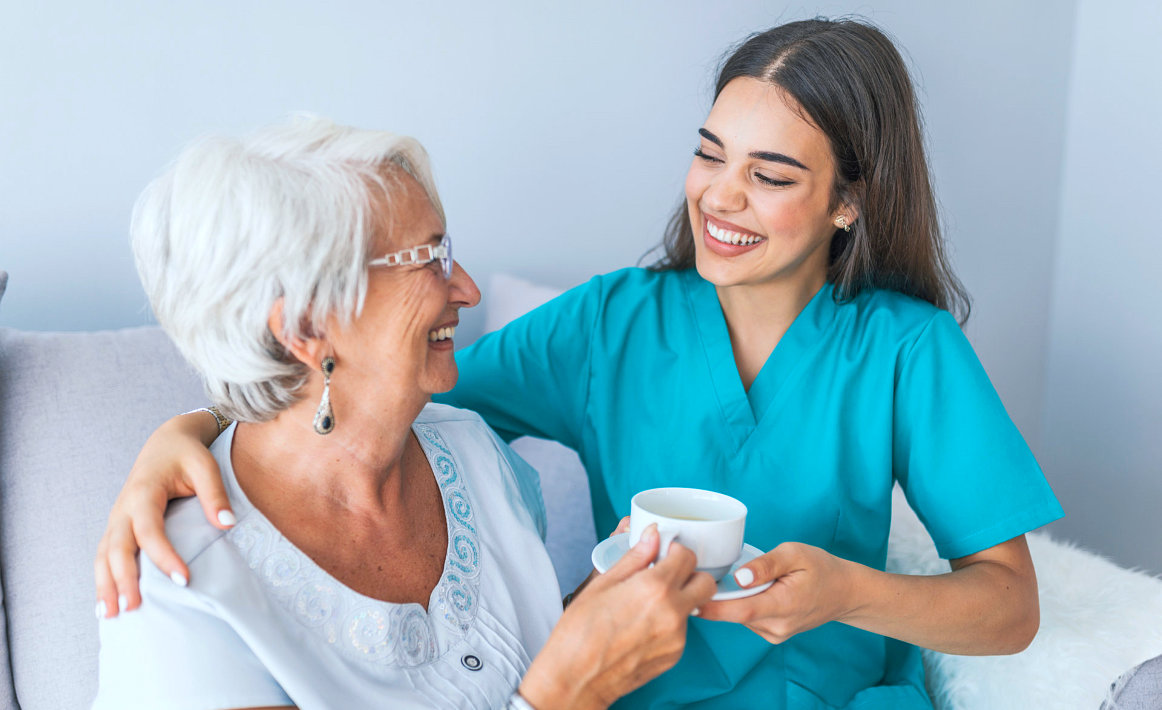 caregiver and senior woman smiling while looking at each other