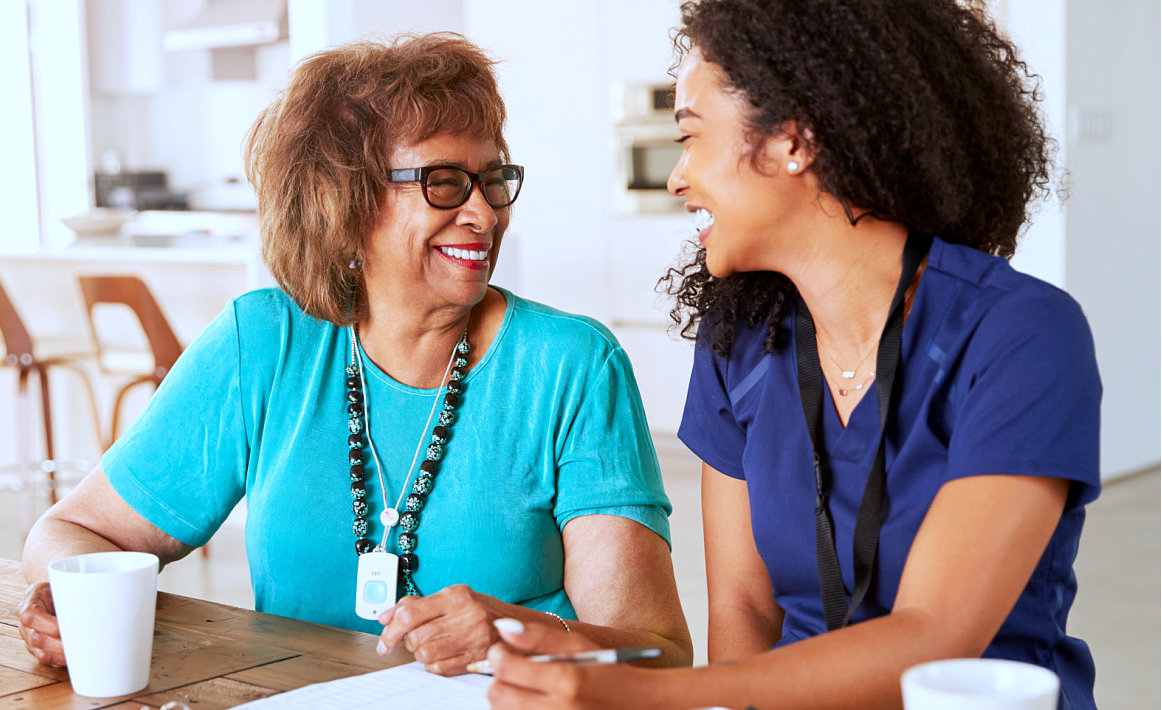 caregiver and senior woman smiling while looking at each other