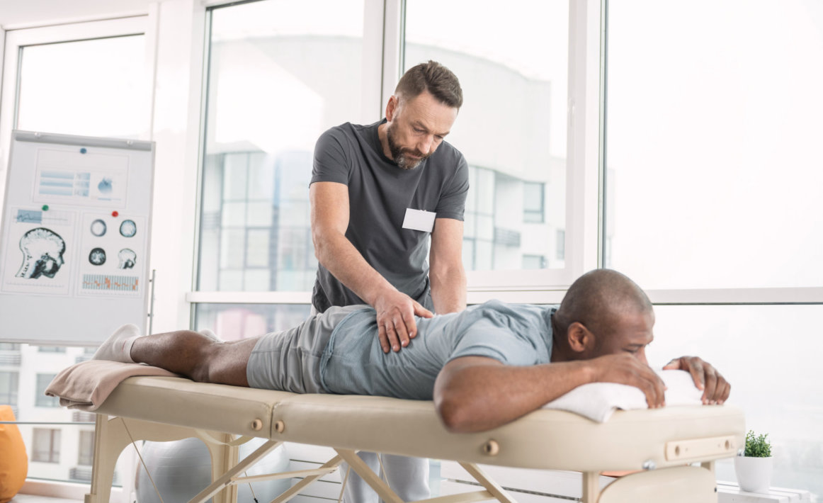 Skilled bearded man doing a back massage for his patient