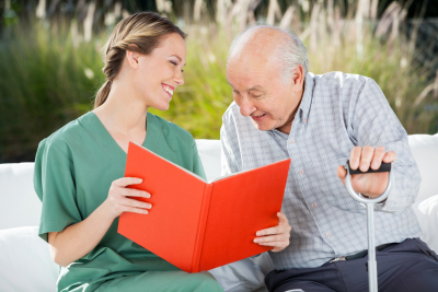 caregiver and senior man smiling while reading