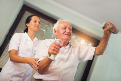 caregiver assisting senior man on doing exercise