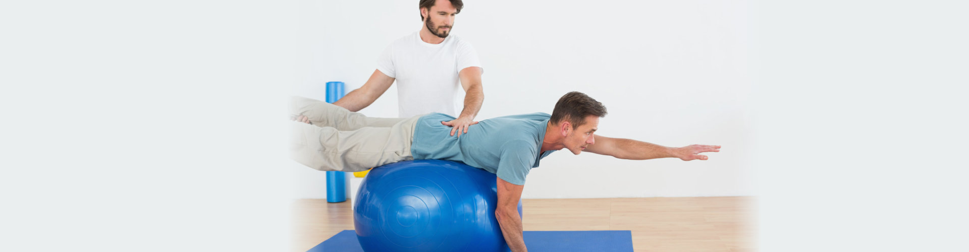 Physical therapist assisting a person on a yoga ball